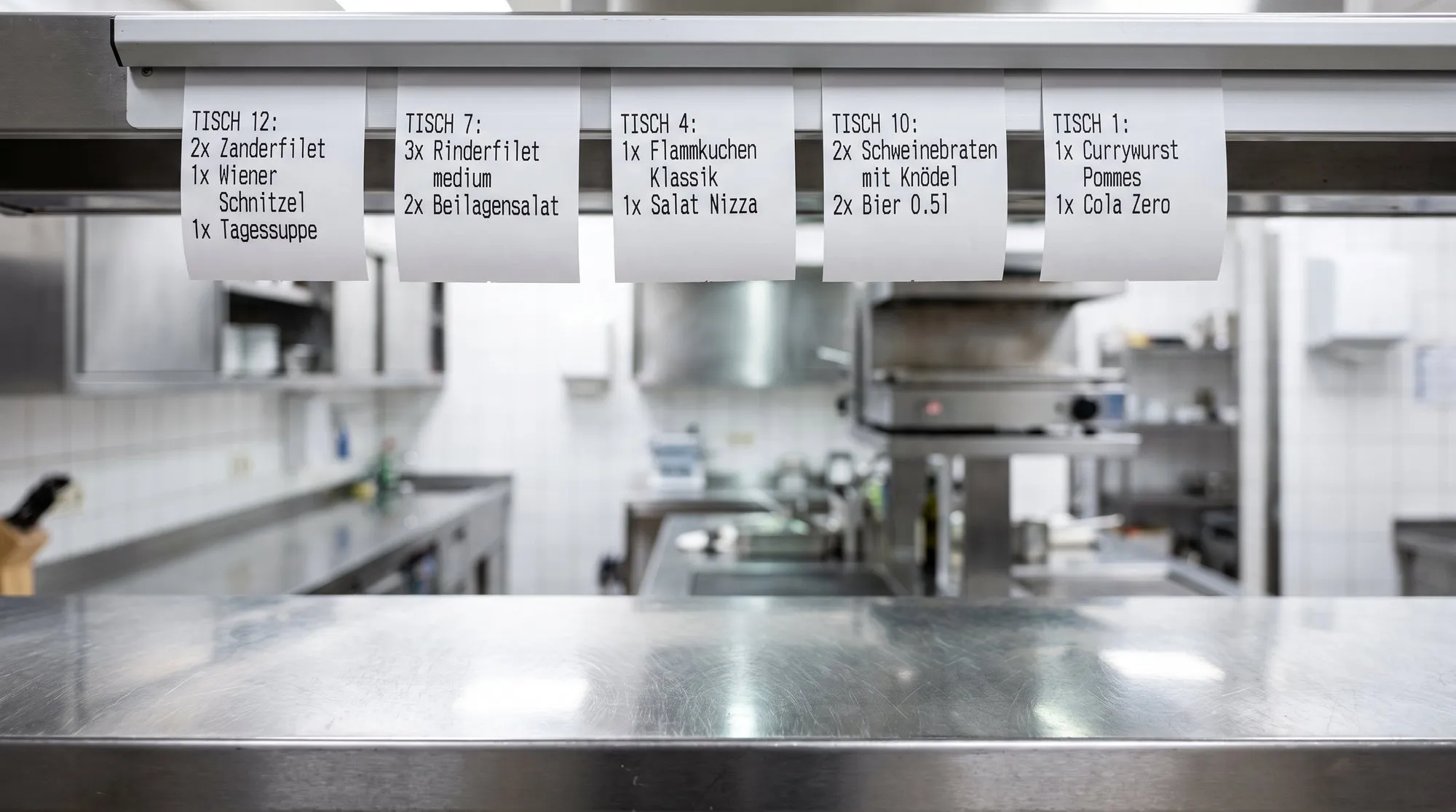 Bon-Leiste mit Bestellzetteln über dem Pass einer Restaurantküche