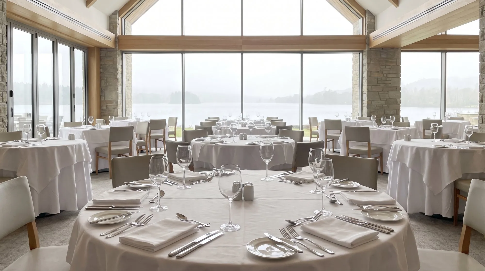 Eingedeckter Speisesaal eines Hotels mit Seeblick am Abend